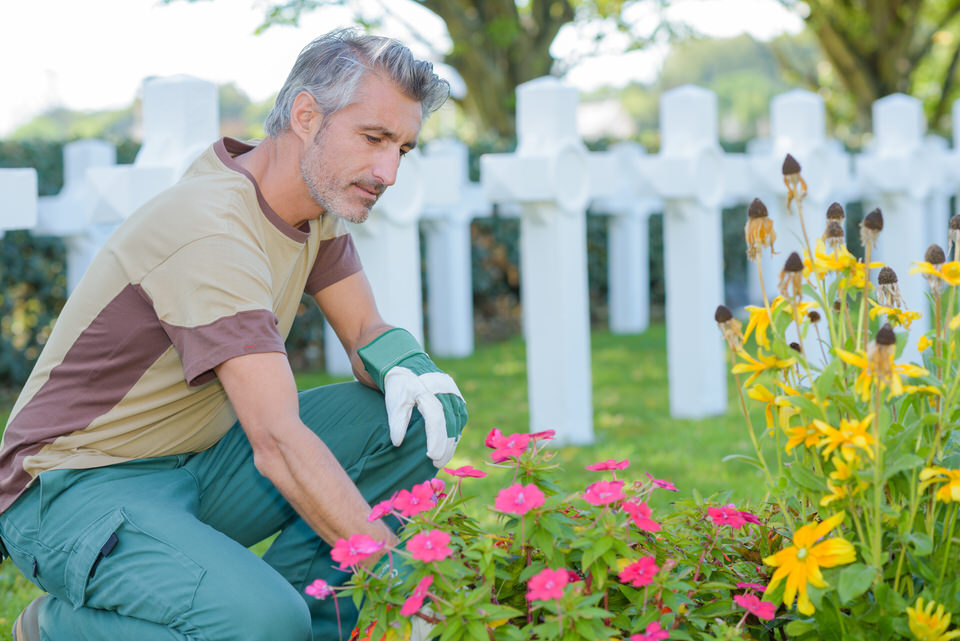 städar gravplatsen, planterar blommor och underhåller graven